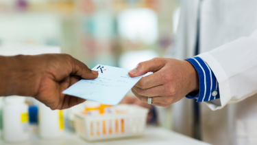 Image of person handing prescription to pharmacist