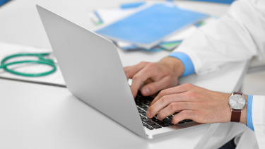 Physician typing on a computer